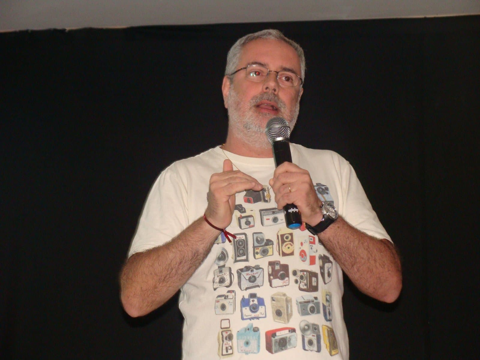 Ruy Jobim de microfone na mão, falando no palco da Unisuam
