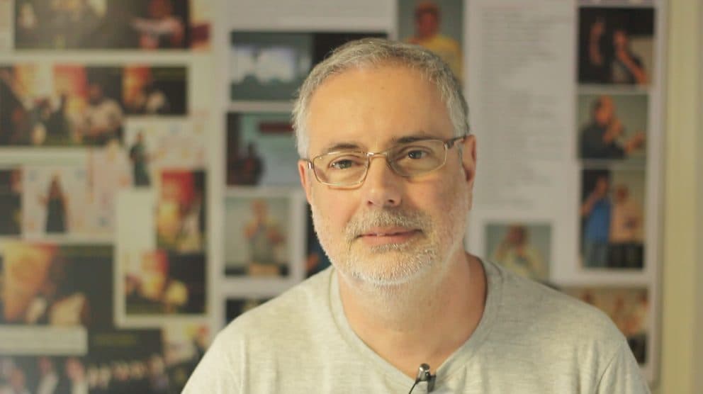 Ruy Jobim em frente a um painel de fotos, gravando