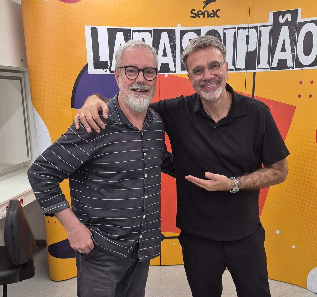 Ruy Jobim e Mauro Beting abraçados em frente ao painel do Senac Lapa Scipião