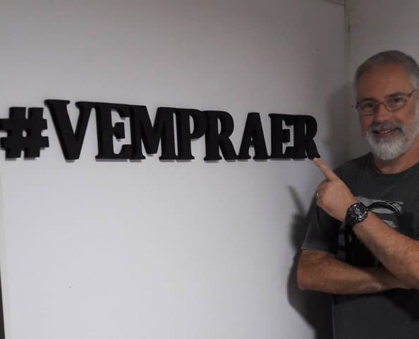 Ruy Jobim apontando para a hashtag #VEMPRAER na parede